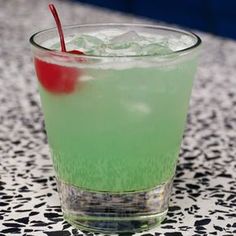 a green drink with a cherry on the rim