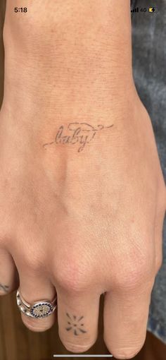 a woman's hand with a small tattoo on her left wrist and the word baby written in cursive writing