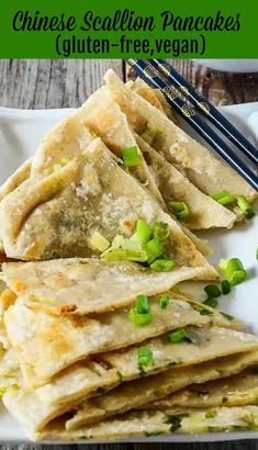 some food is on a white plate with chopsticks and green onions in it