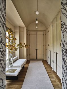 a long hallway with white walls and wood flooring on both sides, leading to a sitting area