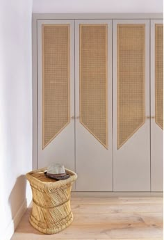 a wicker basket sitting on top of a wooden floor next to a white wall