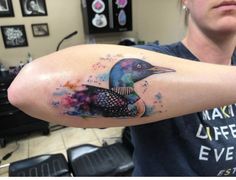 a woman with a colorful tattoo on her arm is looking at the camera and she has a bird painted on her arm