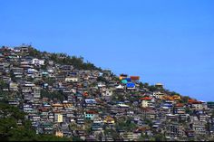 a hill covered in lots of houses on top of a hillside with blue skies above