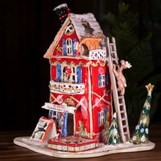 a red christmas house with decorations on it and a ladder leading up to the roof