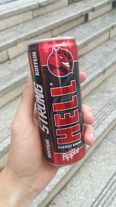 a hand holding up a can of diet drink on some steps in front of stairs