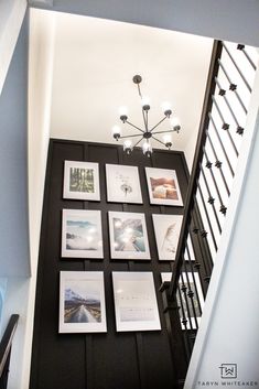 a staircase with pictures on the wall and chandelier