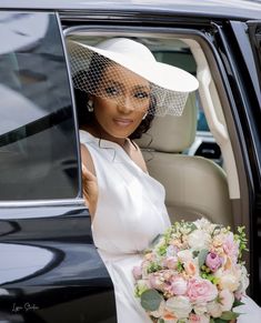 a woman in a white dress and hat sitting in a car