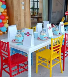 there are many colorful chairs and tables set up for a birthday party with balloons in the background