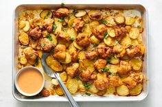 a pan filled with potatoes covered in sauce and garnished with parsley next to a spoon