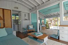 a living room filled with furniture next to a wooden floor covered in blue shutters