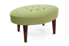 a green ottoman sitting on top of a white floor next to a wooden leg rest