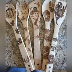 four wooden spoons with different designs on them sitting next to each other in front of a granite counter top