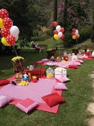 a bunch of balloons are on the ground near some picnic blankets and other items in the grass