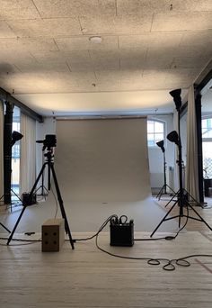 an empty photo studio with lighting equipment in the foreground and large windows to the side