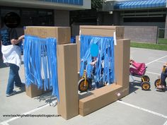 two cardboard boxes with blue ribbons on them and some people standing in the parking lot