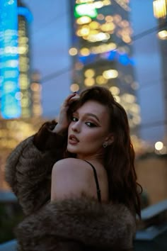 a woman in a fur coat is posing for the camera with her hand on her head