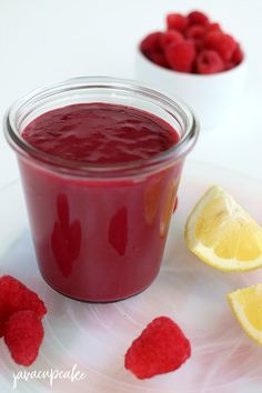 raspberry sauce in a small glass jar next to sliced lemon and raspberries