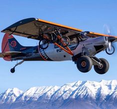 an airplane flying in the air with mountains in the background