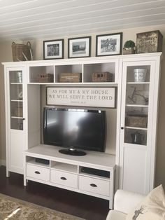 a white entertainment center in a living room with pictures on the wall and shelves above it