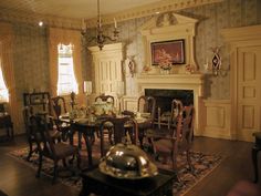 an old fashioned dining room with chairs and table in front of the fire place,