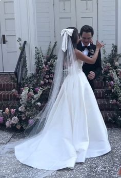 a bride and groom standing in front of some flowers