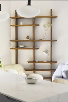 a white table and chairs in a room with shelving on the wall behind it