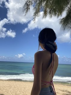 a woman standing on top of a sandy beach next to the ocean