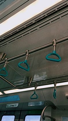 the inside of a bus with blue handles and hooks hanging from it's ceiling