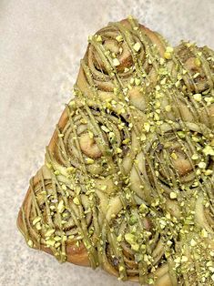 a piece of bread with green toppings sitting on top of a white countertop