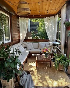 a covered porch with lots of plants and furniture