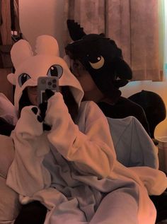 a woman taking a selfie with her cell phone while wearing an animal mask and blanket