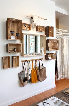 the wall is filled with wooden boxes and purses hanging on it's sides