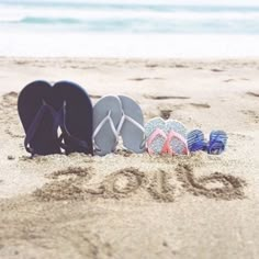 four pairs of flip flops sitting in the sand at the beach that says go