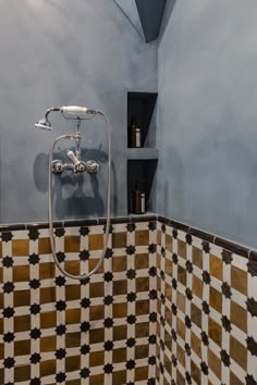 a tiled shower in a bathroom with blue walls and black and white checkered tiles