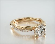 two yellow gold engagement rings with diamonds on the sides and an oval shaped diamond in the middle