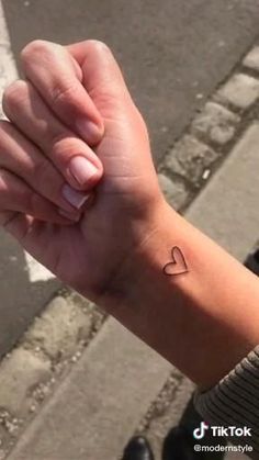 a woman's arm with a small heart tattoo on the left side of her wrist