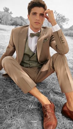 a man in a suit and tie sitting on the ground with his hand to his head