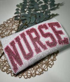 the word nurse is printed on a white t - shirt with pink glitter letters and green leaves