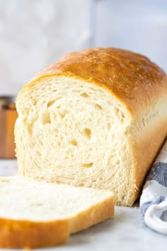 a loaf of white bread sitting on top of a counter next to a piece of bread