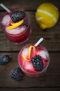 two glasses filled with fruit and ice on top of a wooden table