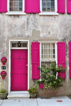 a pink door and window in front of a building with red shutters on the windows