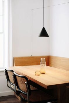 a wooden table with two glasses on it in front of a black light hanging from the ceiling