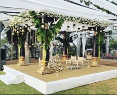 an outdoor wedding setup with white flowers and greenery on the stage for guests to sit down