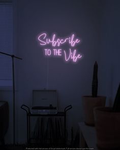 a neon sign that says suppsorbe to the vibe in front of a laptop