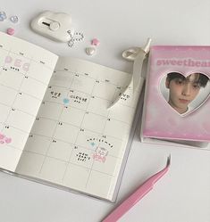 an open notebook with a heart shaped sticker on it next to a pink pen