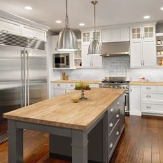 a kitchen with an island and stainless steel appliances in the center, along with hardwood floors