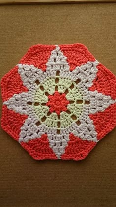 a red and white crocheted doily sitting on top of a cardboard box