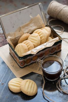 a box of cookies next to a cup of coffee and twine on a table