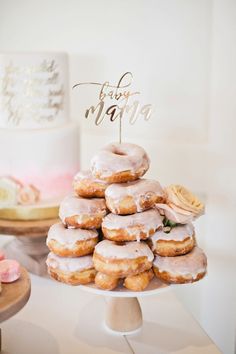 a stack of doughnuts sitting on top of a white cake stand next to a wedding cake