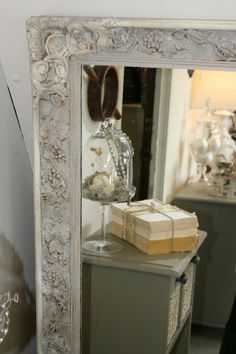 an ornate white frame mirror sitting on top of a dresser